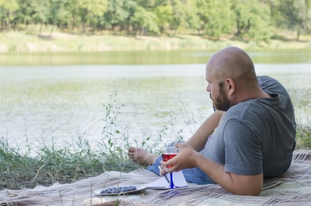 the bald guy writes to a notebook in park lying on a grassの写真素材