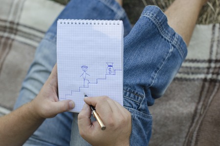 the young guy writes in a notebook in the open airの写真素材