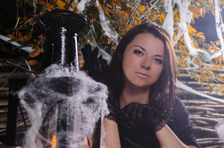 the girl the witch at a table in a suit for Halloween with pumpkin