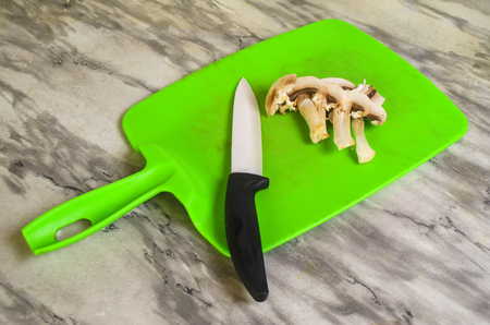 cutting of mushrooms on a green board with a ceramic knifeの写真素材
