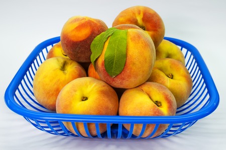 a basket of fresh peaches on a white backgroundの写真素材