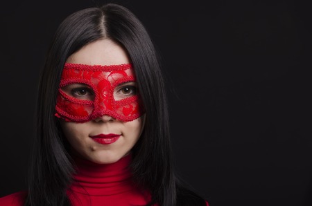 Young girl in a carnival mask on a black backgroundの写真素材