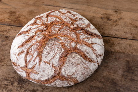 Round rye bread with a crispy crust and flour on a old table. Alsace, France.