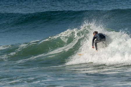 Surfer riding a wave on an Atlantic Ocean beach. Camaret, Crozon, Brittany, France, Europe