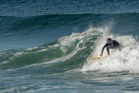 Surfer riding a wave on an Atlantic Ocean beach. Camaret, Crozon, Brittany, France, Europe