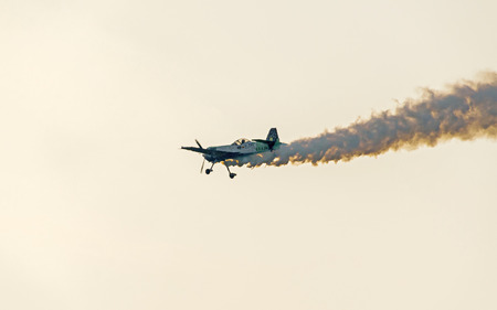 BUCHAREST, ROMANIA - JULY 20, 2016. Airplane with colored trace smoke flying in the blue clouds sky,...