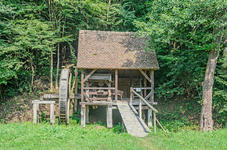 Watermill close up, green forest, wild vegetation, blue clouds sky.の写真素材