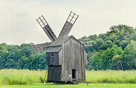 Windmill close up, green forest, wild vegetation, blue clouds sky.の写真素材