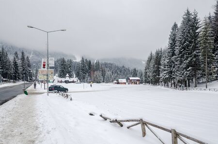 BRASOV, ROMANIA - MARCH 19, 2015: Road in Carpathian Mountains with trees and huts.のeditorial素材