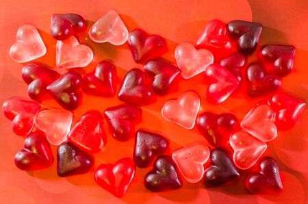 Colored (pink, red and orange), transparent heart shape jellies, close up, texture.