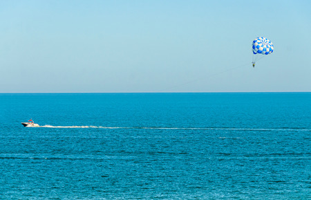 Blue parasail wing pulled by a boat in the sea water, Parasailing also known as parascending or parakiting.の写真素材