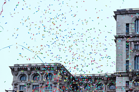 Colored confetti falling, blue sky in a european city, close up background.の写真素材