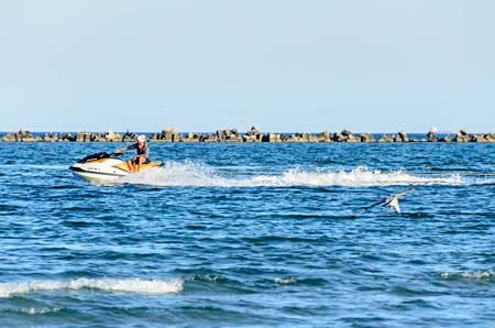 MAMAIA, ROMANIA - SEPTEMBER 15, 2017: Man riding a jet ski over blue Black Sea water, banana boat.のeditorial素材