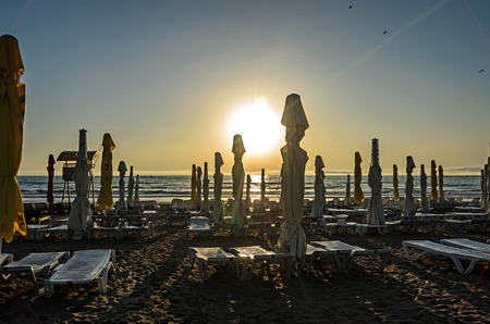 MAMAIA, ROMANIA - SEPTEMBER 15, 2017: Beach of Black Sea with sunbeds and umbrellas, blue clear water and golden sand at sunrise.のeditorial素材