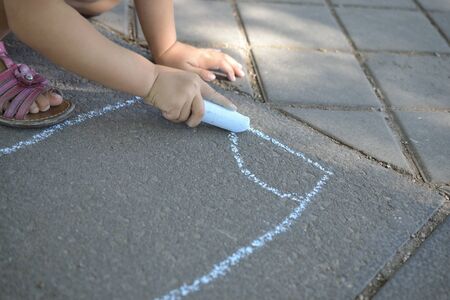Child hand drawing with chalk on the groundの写真素材