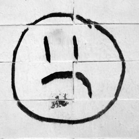 unhappy face drawing on a brick wallの写真素材