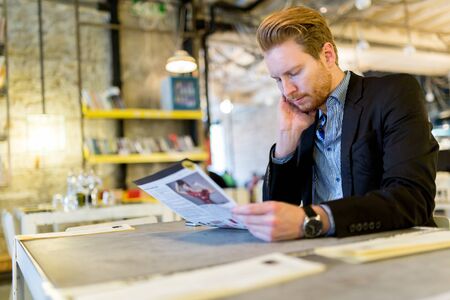 Confused businessman reading the paper in a restaurantの写真素材