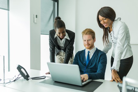 Business people talking and smiling in an office in front of a notebookの写真素材