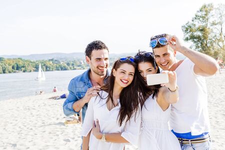 Group of cheerful and beautiful young people taking selfies of themselves