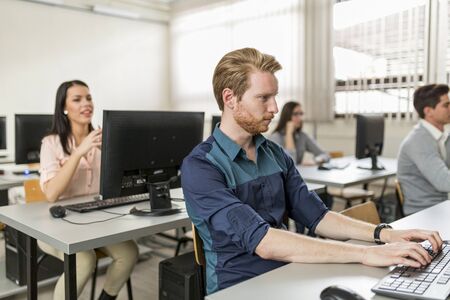 Young handsome student using computer in classroom