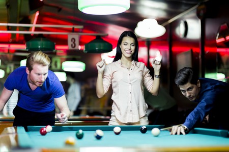 Young people playing billiard in a club pub bar
