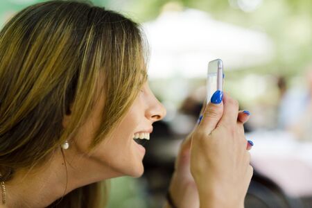 Beautiful young woman texting somebody with her phone and enjoying the conversation