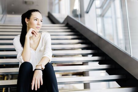 Businesswoman sitting on stairs and thinking. Fashion style photoの写真素材