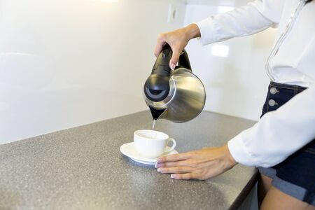 Closeup of hot water being poured out of the kettle in a modern kitchen