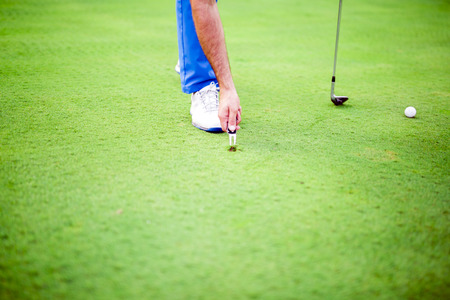 Golf player repairing divot on a green grass surfaceの写真素材