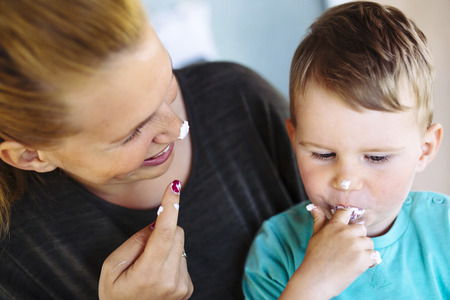 Mother and child eating cake with desert Their fingers and enjoying themselvesの写真素材