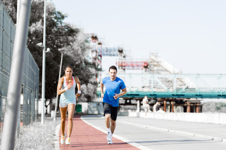 A man and a woman jogging on a city track