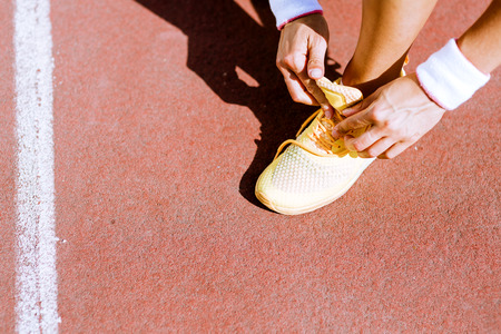 Athlete tying shoe lace with both hands in summerの写真素材