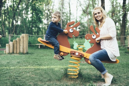 Mother and son playing in the playground and riding a seesawの写真素材