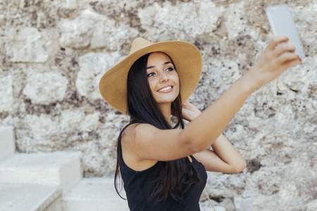 Attractive girl taking selfie while wearing hatの写真素材