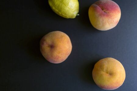 Fresh peaches and a lemon on a black background, top viewの写真素材