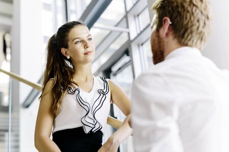 Business colleagues talking on stairs of a modern officeの写真素材