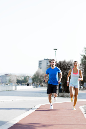 A man and a woman jogging on a city trackの写真素材