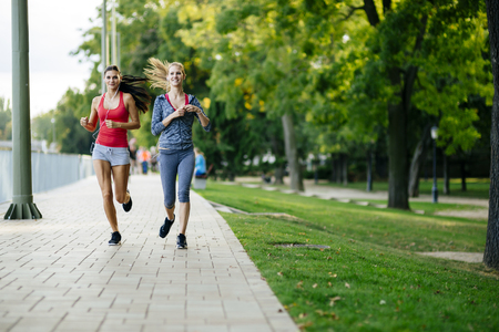 Two women jogging in park and listening to musicの写真素材
