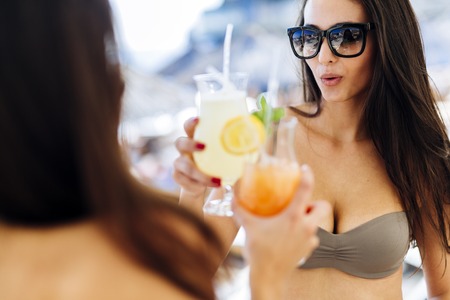 Beautiful women on sunny beach enjoying cocktailsの写真素材