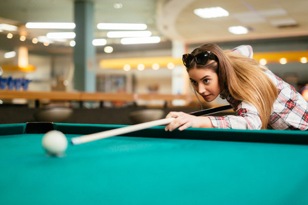 eautiful brunette aiming while playing snookerの写真素材