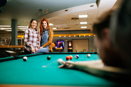 Happy friends enjoying playing pool together