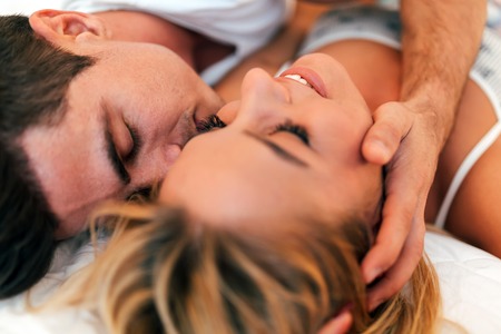 Passionate beautiful couple in bedroom enjoying foreplayの写真素材