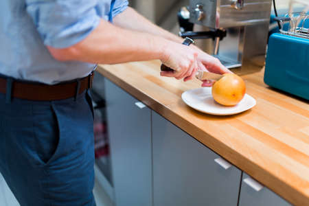 Handsome male in kitchen slicing orangesの写真素材