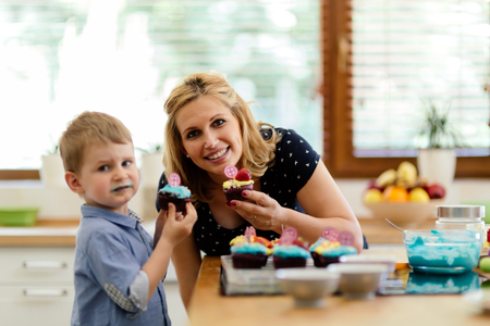 Mother and child joyfully eating muffins just made by themの写真素材
