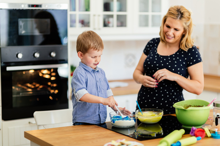 Beautiful child and mother baking in kitchen with loveの写真素材