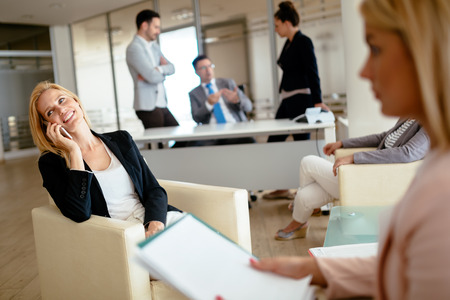 Busy businesswoman has toanswer phone multiple times during workの写真素材