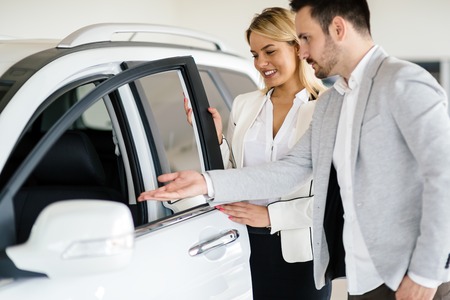 Customer looking at cars at dealership and talking to salesperson