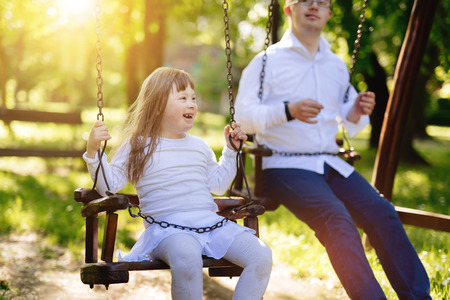 Happy child with down syndrome enjoying swing on playgroundの写真素材
