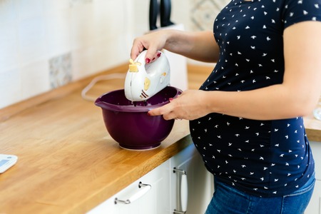 Pregnant woman preparing cookies in kitchen