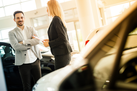 Salesperson showing vehicle to potential customer in dealershipの写真素材